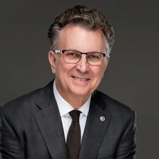 Headshot of man in a suit wearing glasses