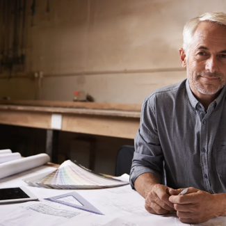 A man sitting at a desk with architecture drawings on the table