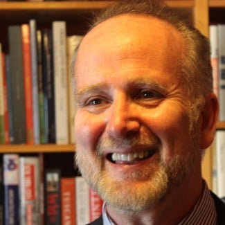 Headshot of man with beard in front of bookcase