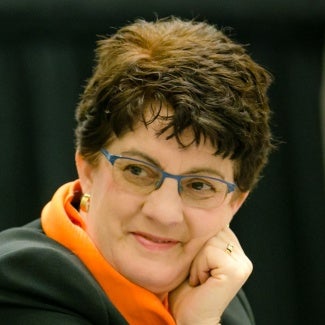 headshot of woman with short hair and glasses resting her chin on her hand