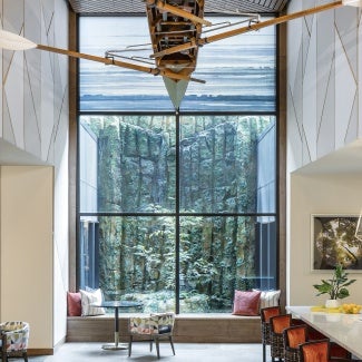 Interior view reflecting a counter/stool area on the right, another common area on the left and in the middle an overarching forest view through window quadrants.