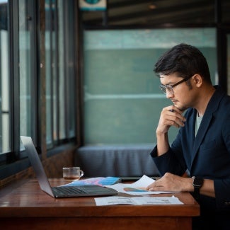 Asian young businessman working with laptop at office, office worker browsing in laptop for necessary information. 