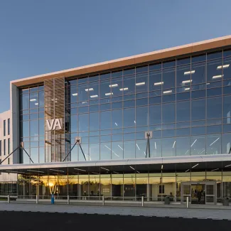 THE BUILDING'S GLASS CORNER IS FRAMED WITH CRISP WHITE LINES TO SIGNIFY ENTRY TO VISITING VETERANS. THE ARCHITECTURAL GESTURE IS AS IF THE BUILDING IS STANDING AT ATTENTION AND SALUTING.