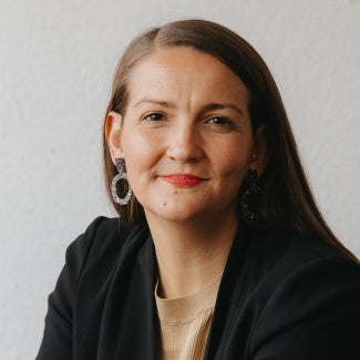 Headshot of a woman with long dark hair in a dark jacket