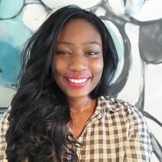 Headshot of a woman with long dark hair, wearing a checkered blouse.