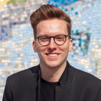 Headshot of a man wearing glasses and a dark blazer