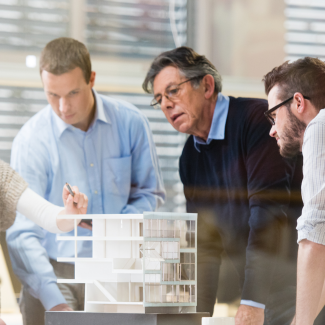 Four architects around a table discussing a model