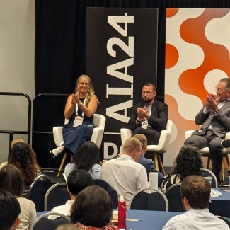 Men and women sitting on stage at an AIA conference
