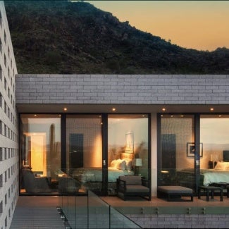 Home with warm light coming from the windows beneath a sunset