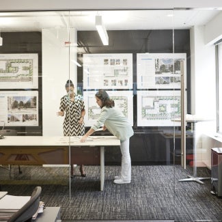 Two architects having a conversation over architectural drawings in their office 