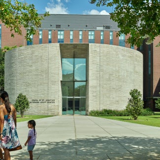 The Chapel of St. Ignatius and the Gayle and Tom Benson Jesuit Center: The main entry connects directly to the pathway of the existing quad. Clad with a large handmade bronze Cross, its texture and patina will evolve with the elements, expressing the sublimity of nature.
