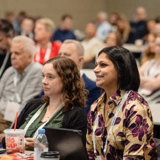 two women attendees in crowded room at a conference session