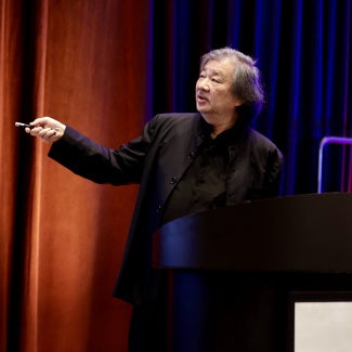 shigeru ban japanese architect giving presentation against colorful curtain background