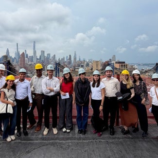 group of architecture students in hard hats in front of new york city skyline